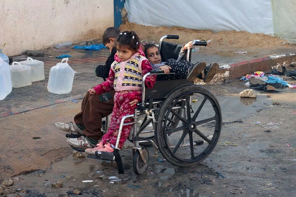  Palestinian children sit in a wheelchair while they make their way to collect water, amid the ongoing conflict between Israel and the Palestinian group Hamas, in Rafah, southern Gaza Strip.  REUTERS 